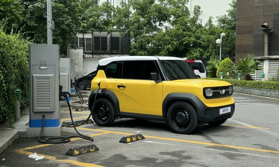 VinFast VF3 màu vàng đang được sạc tại một trụ sạc công cộng